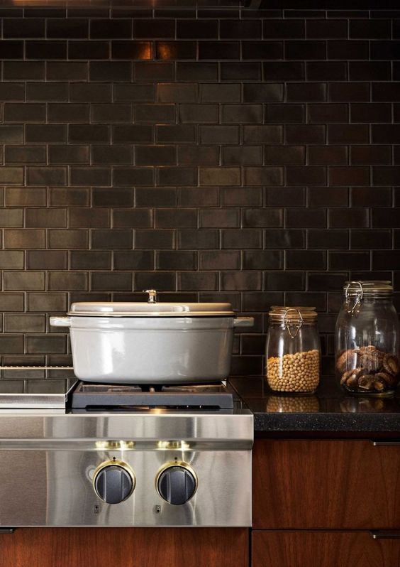 rich-toned cabinets, grey stone countertops and black subway tiles for the backsplash make up a vintage kitchen
