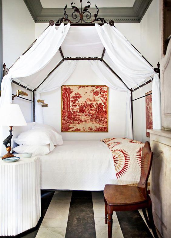 a cozy vintage bed with white curtains and beautiful forged decor on its top makes the bedroom refined