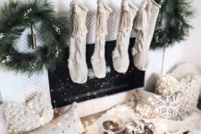 15 a magical fireplace with knit stockings, evergreen wreaths, a greenery runner and fluffy pillows and lights