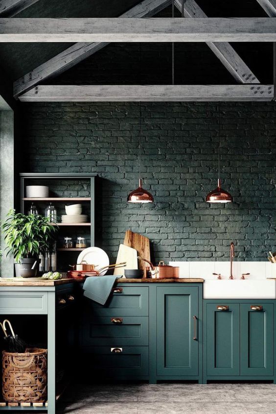 a black brick backsplash matches the forest green cabinets and wooden countertops creating a moody feel in the space