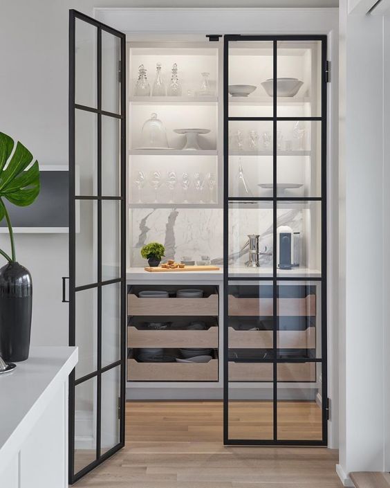 a stylish pantry with shelves, pull out drawers and framed glass doors that allow seeing what's inside all the time