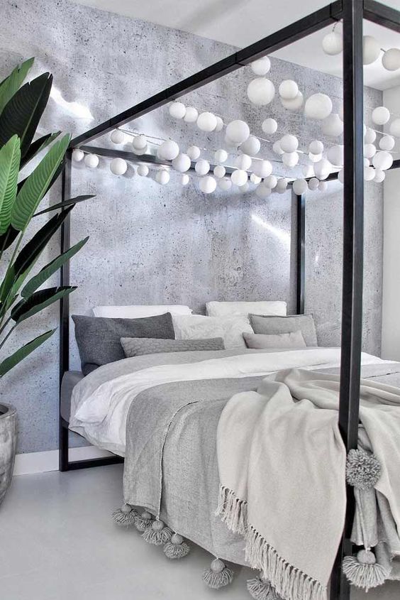 a black canopy bed with white bulb garlands over it is a fun idea to add light without any lamps around
