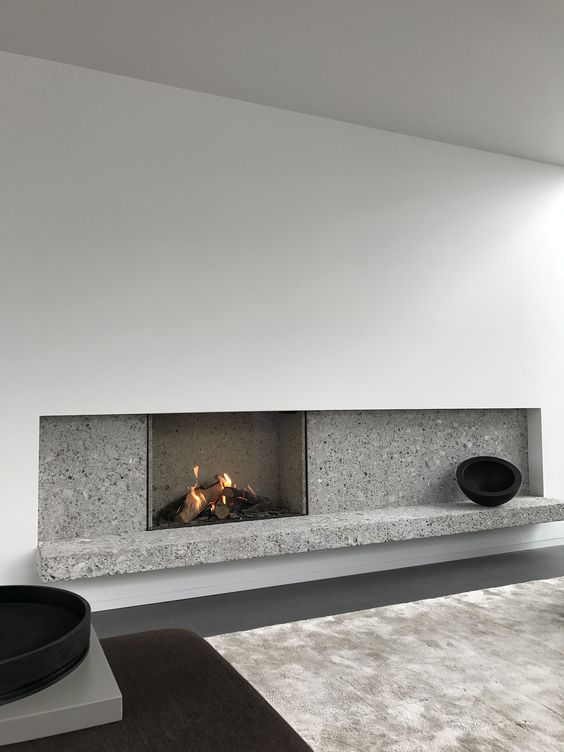a minimalist fireplace with white paneling and grey stone plus some black touches for drama