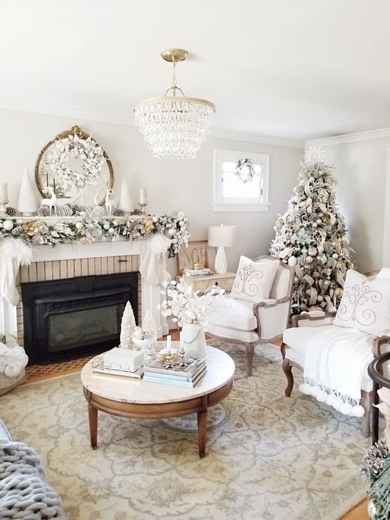 a refined neutral living room with a flocked Christmas tree, a garland with ornaments on the mantel and a snowy wreath