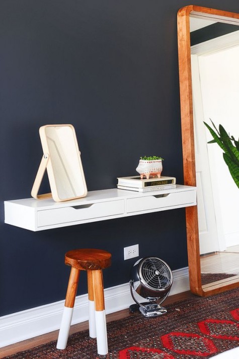 a small vanity made of an IKEA Ekby piece attached to the wall and a small natural stool with color blocked legs for a makeup nook