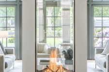 23 a large glass encased double-sided fireplace is a statement piece for any space