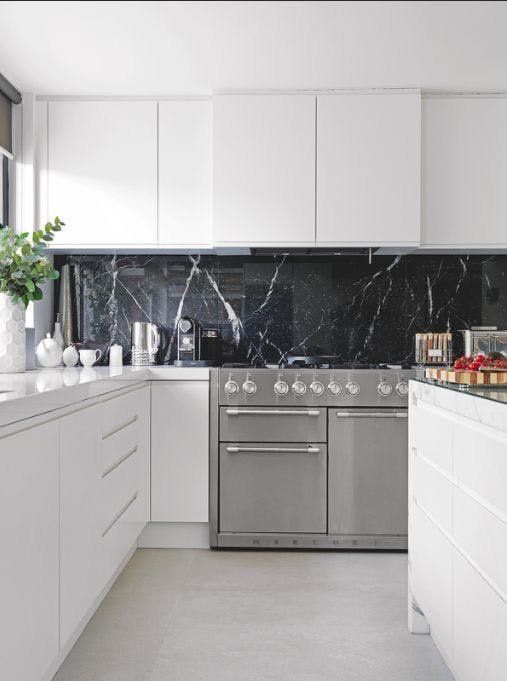 a pure white minimalist kitchen with a black marble backsplash that adds a refined and chic touch