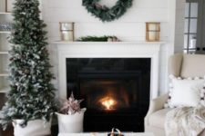 23 a snowy Christmas tree with pinecones and a matching wreath over the fireplace for clean and natural winter decor