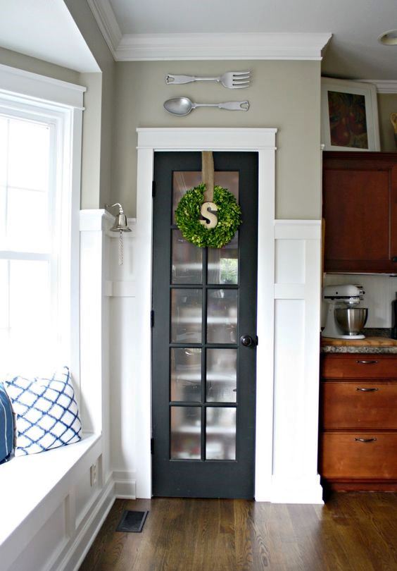 A mini built in pantry with a graphite grey French door and a greenery wreath for a farmhouse kitchen