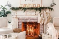 24 cozy winter fireplace styling with white candles, a greenery garland and candles, stockings, white pillows