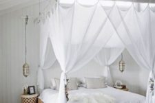24 sheer white curtains match the white boho bedroom and hanging Moroccan lamps continue the decor theme