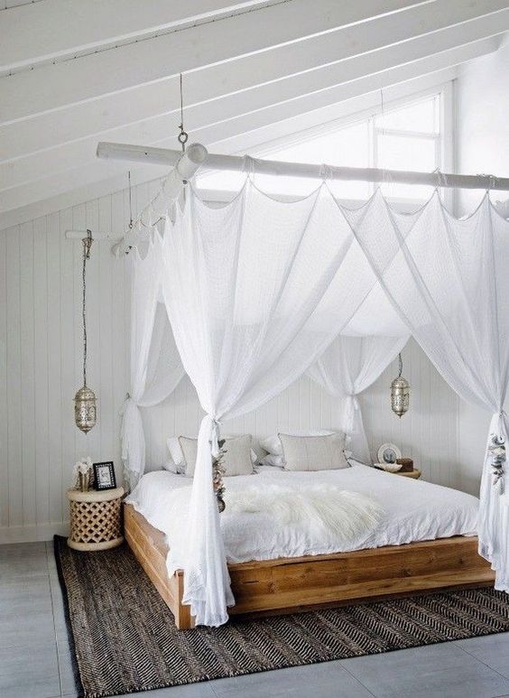 sheer white curtains match the white boho bedroom and hanging Moroccan lamps continue the decor theme