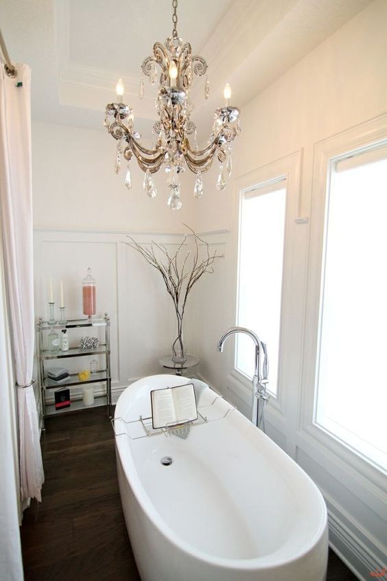 a contemporary bathroom made chic with a vintage crystal chandelier over the bathtub