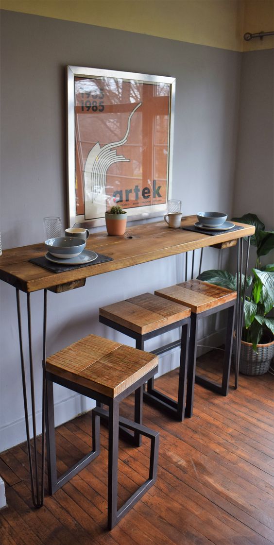a tall industrial console table on hairpin legs and matching tall stools of wood and metal