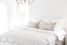29 a neutral farmhouse bedroom with a chic white vintage chandelier that adds an elegant touch