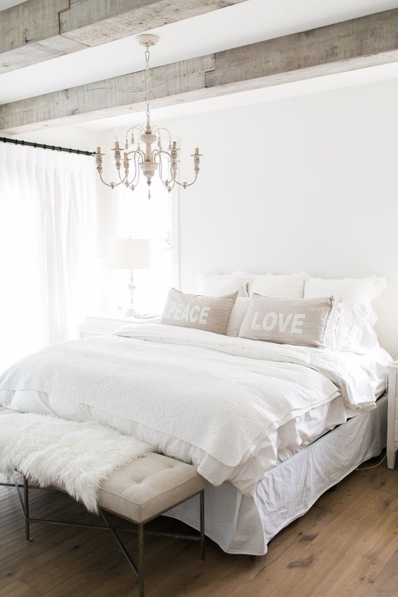 a neutral farmhouse bedroom with a chic white vintage chandelier that adds an elegant touch