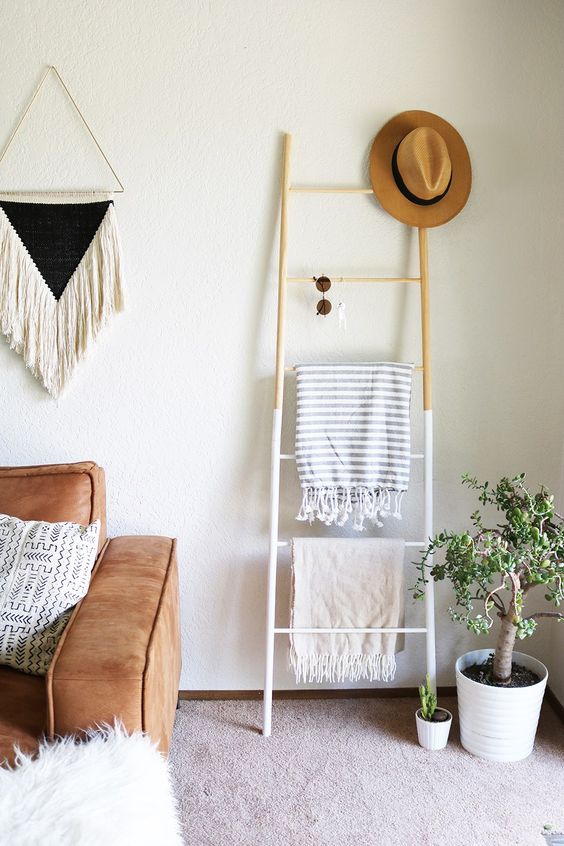 a small color block ladder with blankets, sunglasses and a hat doubles as a storage unit and as decor