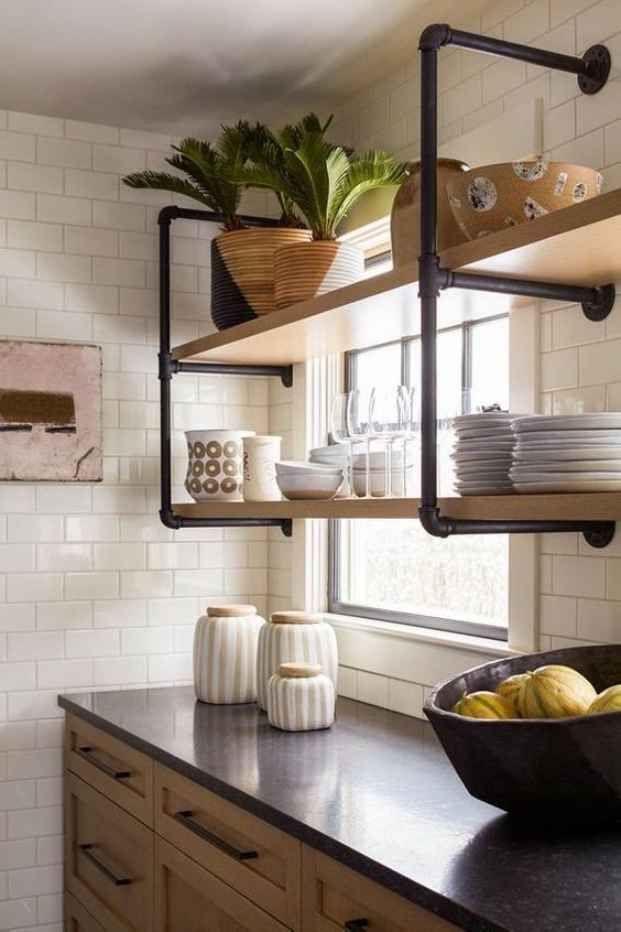 a wall-mounted shelving unit of black pipes and wood is a stylish idea for adding an industrial touch to the kitchen