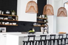 a black and white kitchen with sleek white cabinetry, a white kitchen island, black stools, pendant lamps, a black tile backsplash and open shelves