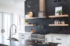 a black and white kitchen with white cabinetry, a black tile backsplash, a black kitchen island and stone countertops