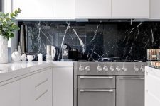 a black marble kitchen backsplash is a very luxurious touch to these ultra-minimalist white cabinets