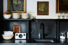 a black vintage-inspired kitchen with a black marble backsplash and countertops for a refined touch