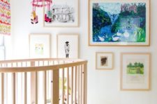 a bright and whimsy nursery with colorful layered rugs, bright artworks, a colorful mobile and curtains