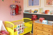 a bright nursery with a yellow bed, a quilted rug, colorful artworks and colorful books on the ledges
