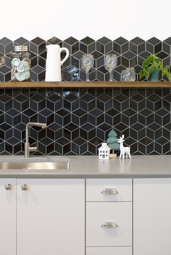 A chic off white kitchen with grey countertops and glossy black geometric tiles on the backsplash is amazing