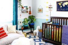 a colorful nursery with a printed rug, bright blue curtains, bedding and colorful pots and mobiles