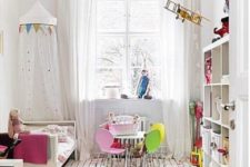 a fun nursery with colorful buntings, a bright striped rug and bedding plus colorful chairs by the table