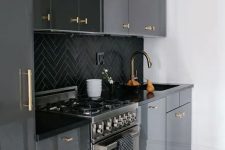 a glossy black kitchen with black chevron tiles on the backsplash and gold fixtures is a cool and chic idea in a classic color