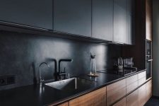 a minimalist kitchen with black and stained sleek cabinetry, a black stone backsplash and countertops plus black fixtures