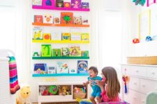 a super colorful nursery with rainbow shelves, a bright rug, bedding and colorful toys