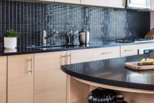 an MDF kitchen with glossy back tiles on the backsplash and black countertops, a matching kitchen island