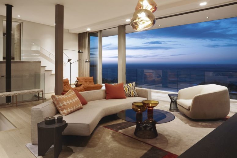 The living room features gorgeous views, there is chic geometric furniture and catchy pendant lights
