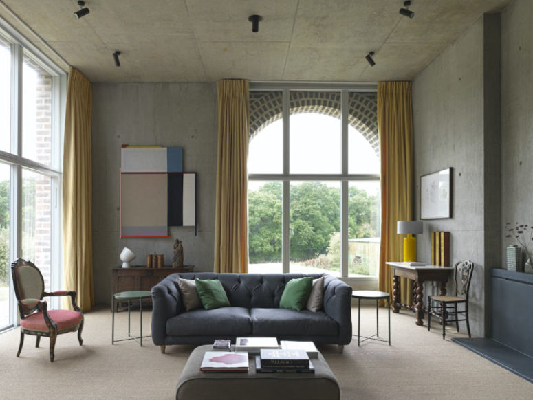 The living room is done with mustard curtains, a mix of refined and modern furniture in muted colors and bright artworks