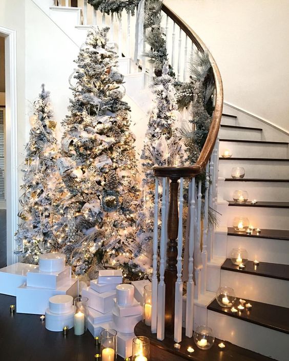 a chic winter fairy tale entryway with tree flocked Christmas trees, lights and neutral ornaments plus candles around