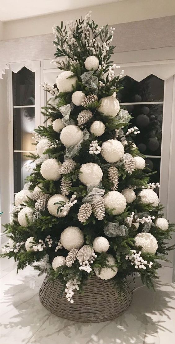 a bold Christmas tree with white berries, bleached pinecones and oversized white pompom ornaments for a cute look