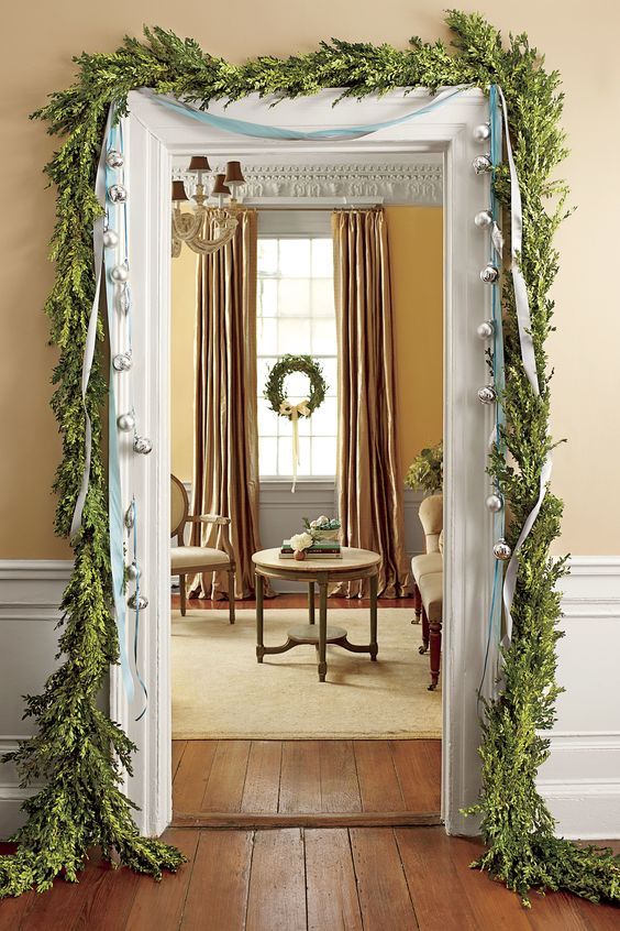 a greenery garland framing the doorway and some large bells hanging on ribbons for a chic and refined look