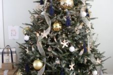 04 a chic beach Christmas tree with lights, navy tassels, starfish ornaments, oversized metallic ones and ribbons and a calligraphy topper