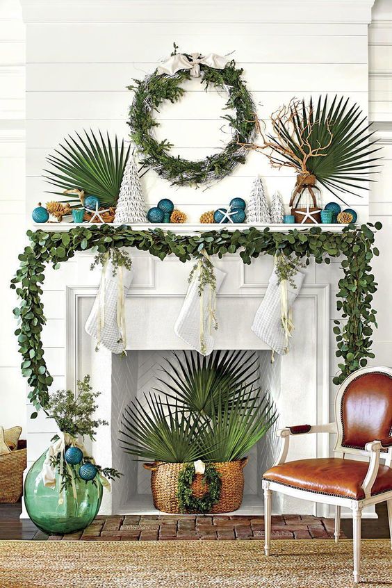 a greenery garland on the mantel, a greenery wreath and tropical leaves for beach Christmas styling