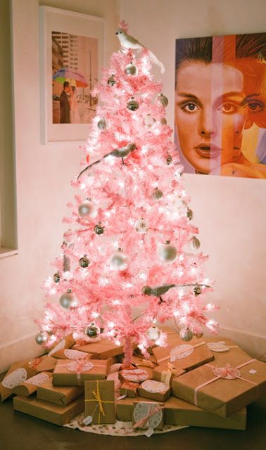 a pastel pink Christmas tree with white and metallic ornaments and quirky birdie ornaments plus lights