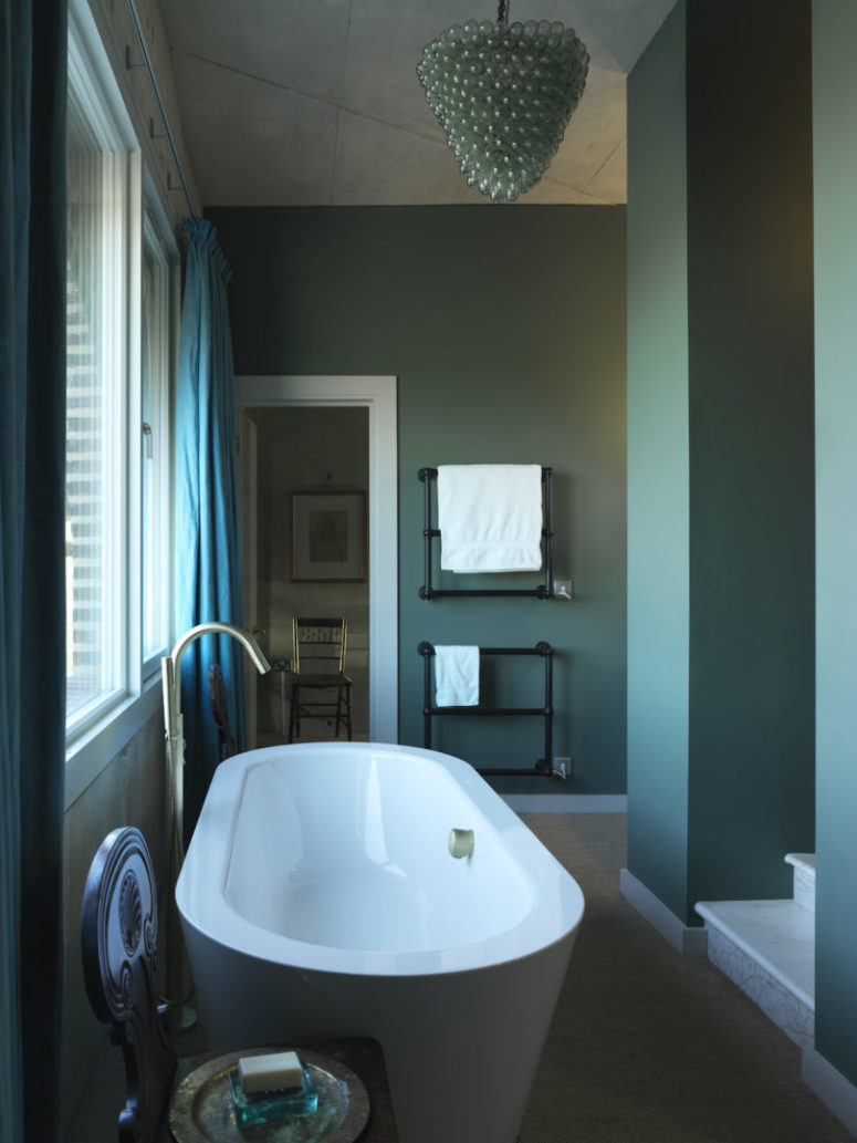 The bathroom is done in blue, with vintage details and a large oval bathtub plus gold touches