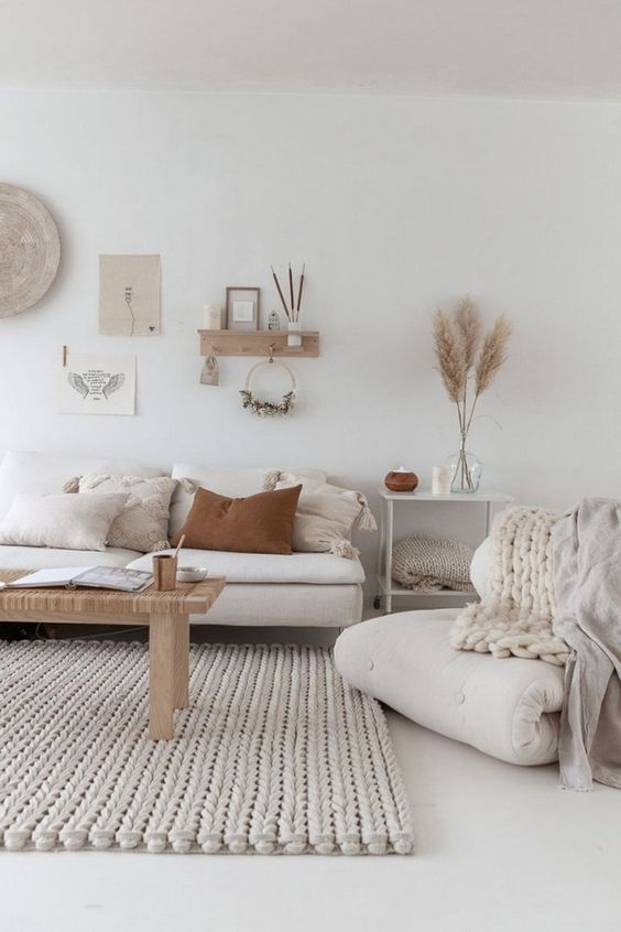 a neutral boho living room with a chunky rug, wood and woven elements and some muted tones
