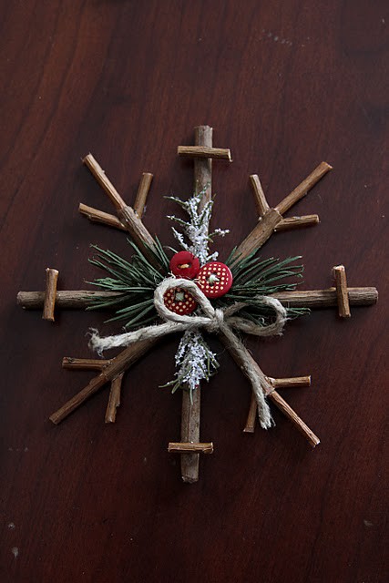 a simple stick snowflake ornament with evergreens, red buttons and twine can be easily DIYed by you or your kids