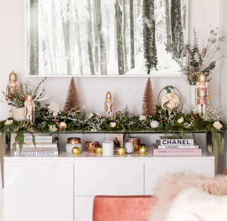 a greenery garland with white blooms and berries on the console table to brign a festive spirit to your living room or entryway