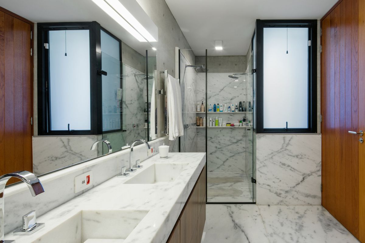 The bathroom is done with white stone and marble and rich colored wood for a timeless feel and look