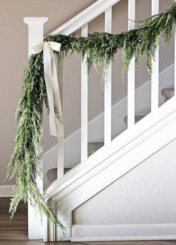 a greenery garland with white bows to style your railing in farmhouse style with a touch of vintage
