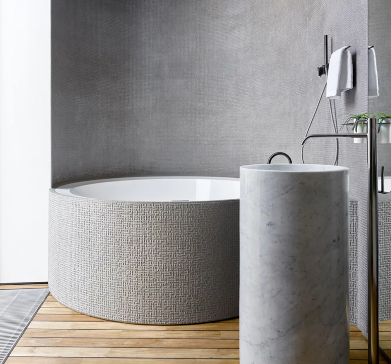 The bathroom features a tile clad round bathtub and a free-standing round sink of white marble